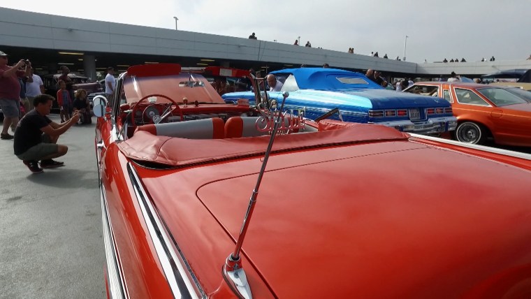 Lowrider owners display their cars at the "High Art of Riding Low: Ranflas, Corazon E Inspiracion" exhibit at the Petersen Automotive Museum in Los Angeles