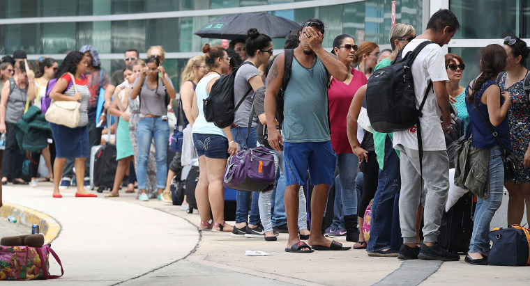 Image: People wait in line to get a flight out of the Luis Munoz Marin International Airport