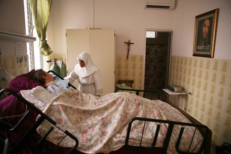 Image: Sister Gloria Flores checks in on a  patient at the Hermanitas de los Ancianos Desamparados facility which cares for the elderly