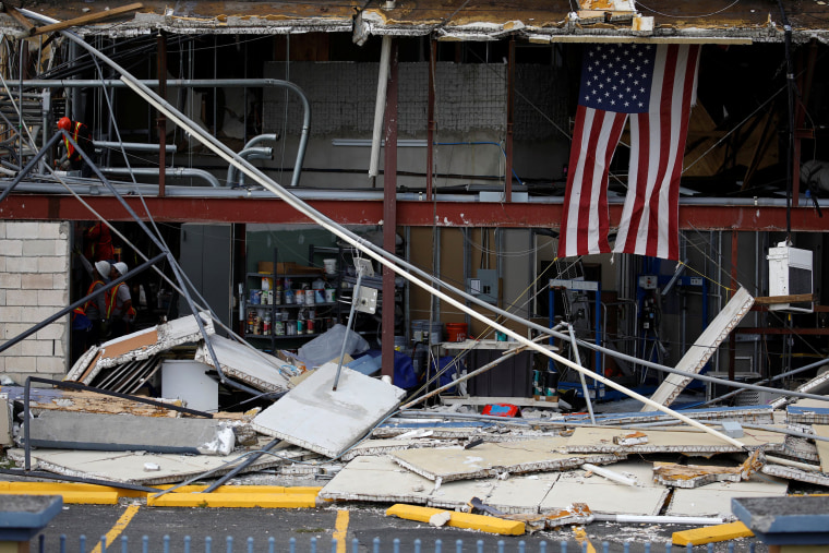 Image: A U.S. flag is seen next to workers making repairs on a damaged church after the area was hit by Hurricane Maria in Carolina