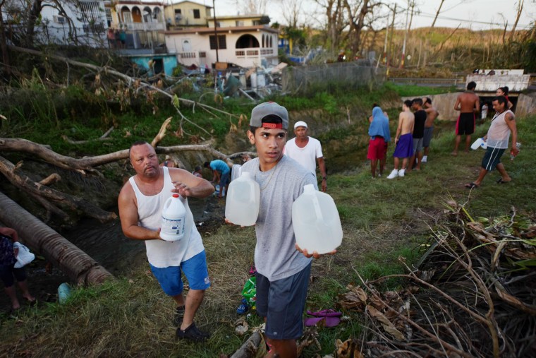 Image: People carry water in bottles retrieved from a canal due to lack of water following passage of Hurricane Maria, in Toa Alta, Puerto Rico