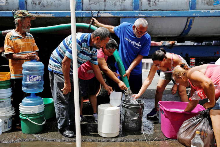 Image: People queue to fill containers with water from a tank truck at an area hit by Hurricane Maria in Canovanas