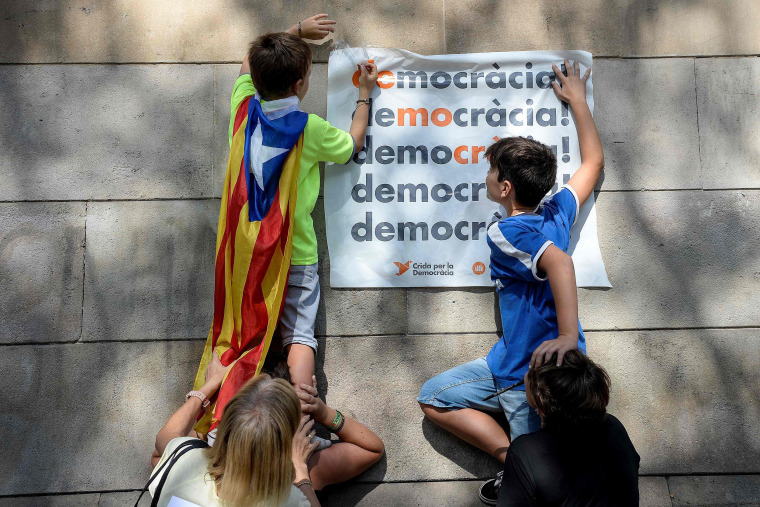 Image: Pro-referendum demonstrators display a placard reading "Democracy" 