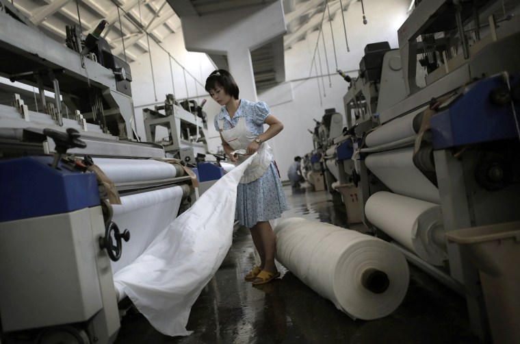 Image: A worker stretches out a bale of cloth at the Kim Jong Suk Pyongyang textile factory