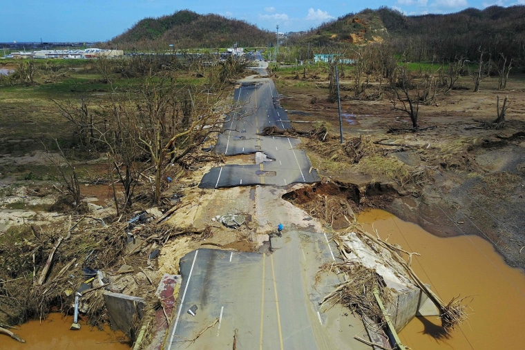 Image: A man rides his bicycle through a damaged road in Toa Alta, Puerto Rico