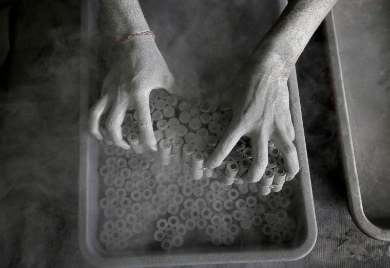 Image: A worker removes paper rolls after filling them with gunpowder mixture to make firecrackers at a factory on the outskirts of Ahmedabad