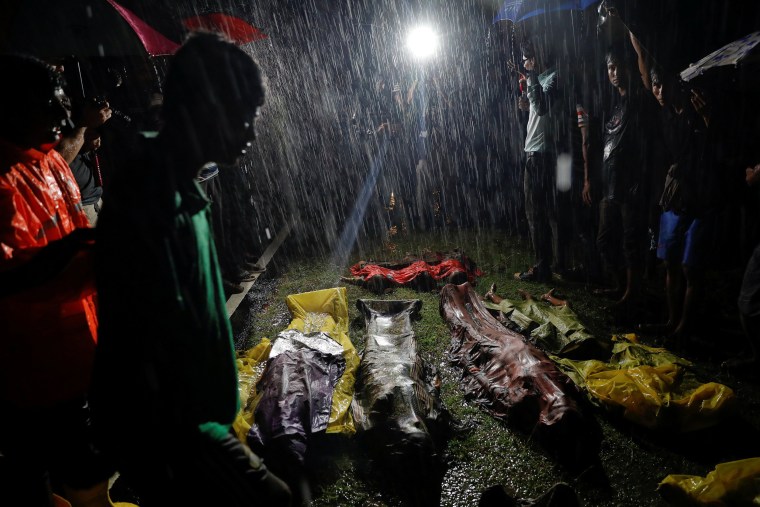 Image: People gather under heavy rain around bodies of Rohingya refugees after their boat with passengers fleeing from Myanmar capsized off the Inani beach near Cox's Bazar