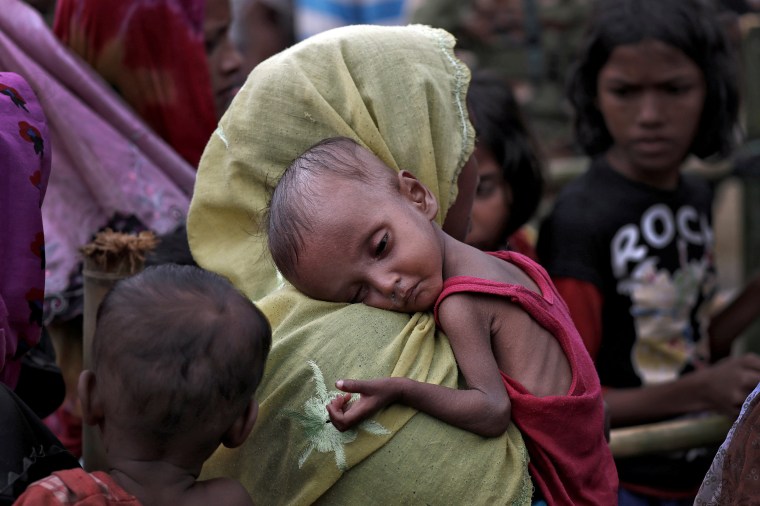 Image: A woman carries an ill Rohingya refugee child through a camp in Cox's Bazar, Bangladesh