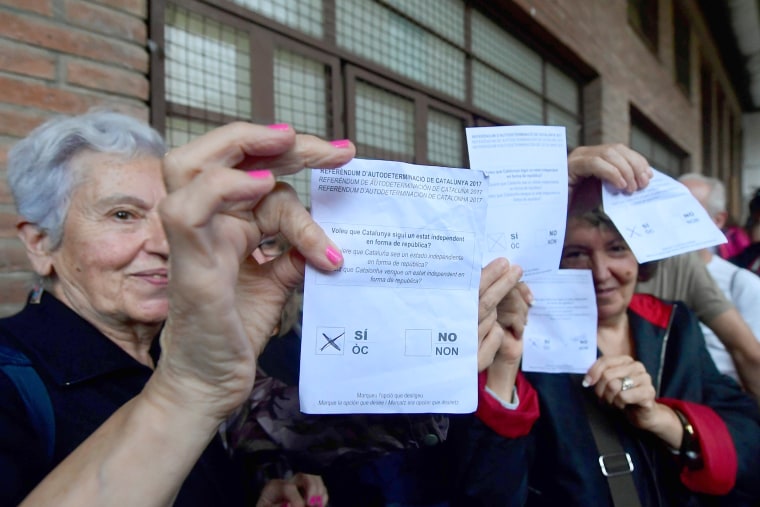 Image: Women hold ballots at a polling station in Barcelona.