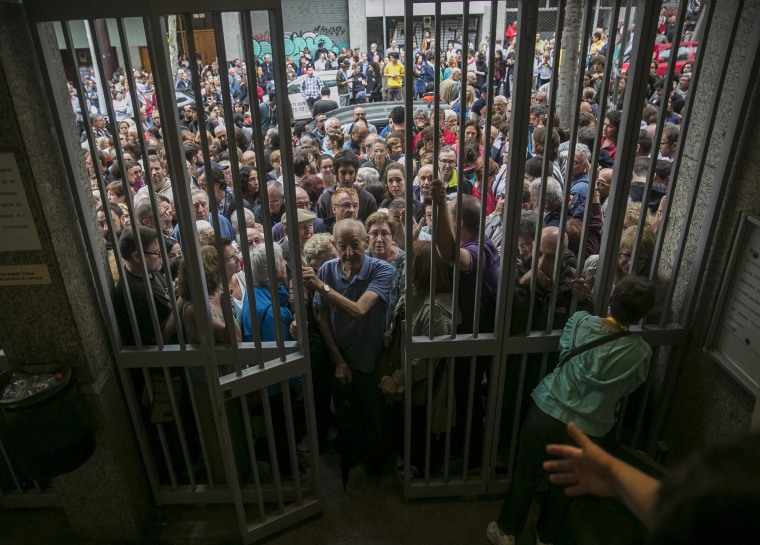 Image: Catalans queue to vote at the Moises Broggi secondary school in Barcelona.