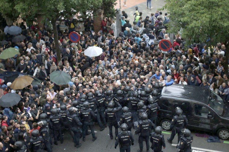 Image: Spanish National Police prevent people from entering a voting site.