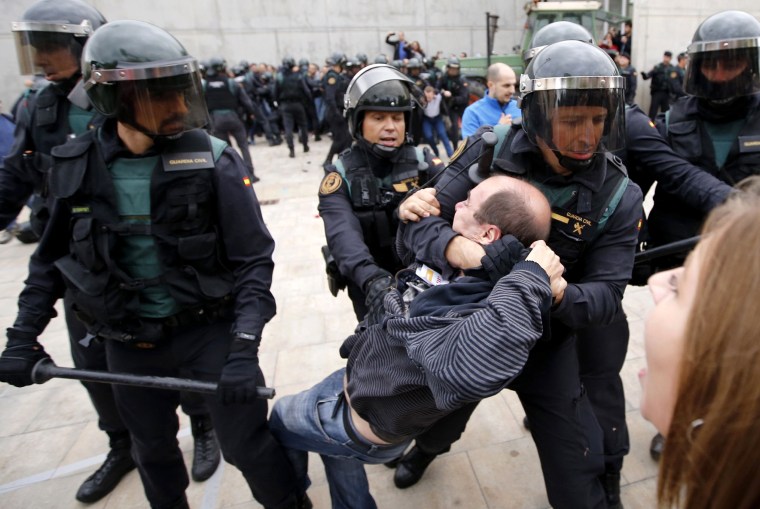 Image: Spanish Guardia Civil guards drag a man outside a polling station in Sant Julia de Ramis.