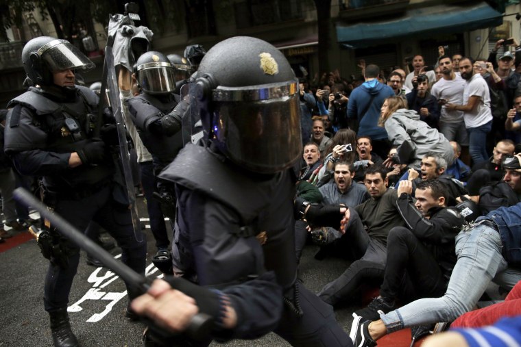 Image: Police try to remove pro-referendum supporters sitting down on a street in Barcelona.