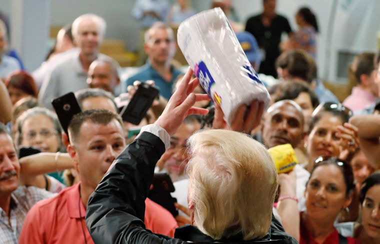 Image: U.S. President Donald Trump throws rolls of paper towels to a crowd of local residents