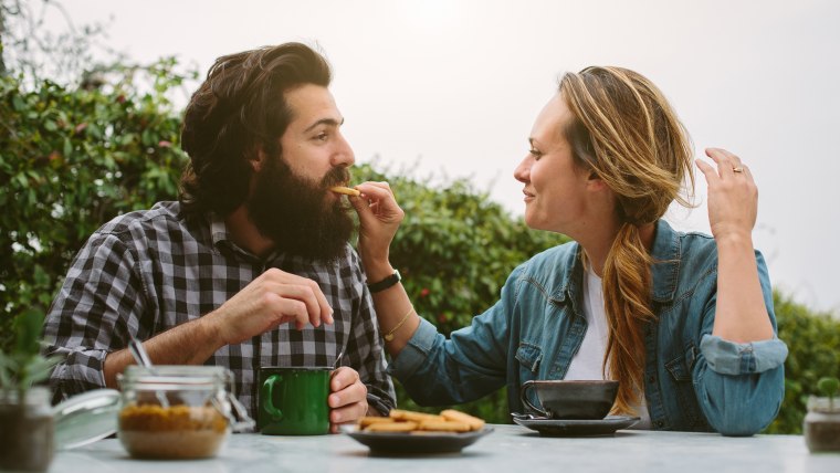 Young couple feeding each other biscuits in garden