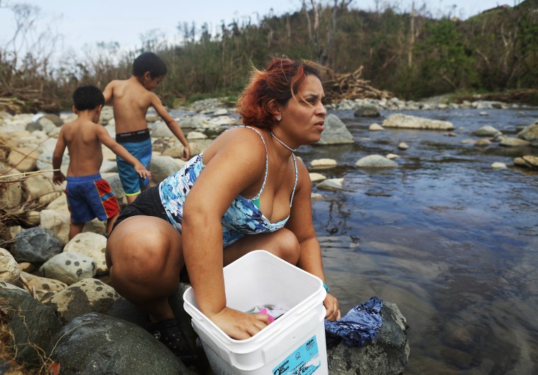 Image: A woman washes clothes with her sons in the Espiritu Santo river in Puerto Rico