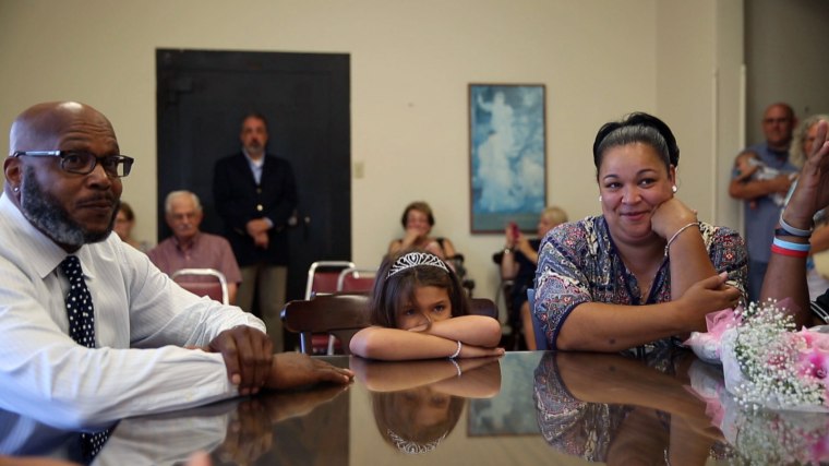 Surrounded by family and friends, Cleo Davis, 51, and Elana Davis, 44, listen as a judge presents them with a certificate confirming the adoption of their 7-year-old granddaughter Sophia.