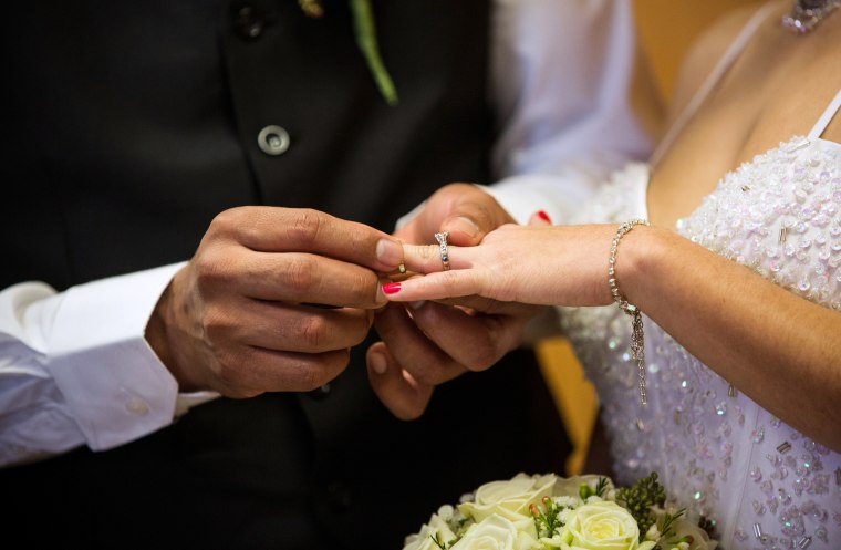 Image: A couple exchanges rings at a ceremony in Newark