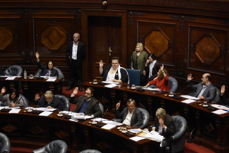 Image: Sen. Michelle Suarez, center back, in white scarf, votes during a Senate session in Montevideo