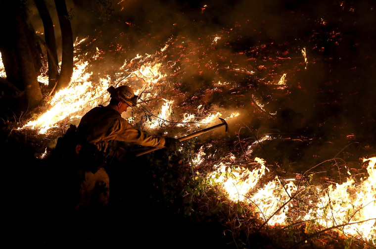 Image: A CalFire firefighter uses a hand tool as he monitors a firing operation while battling the Tubbs Fire on Oct. 12, 2017 near Calistoga, California.