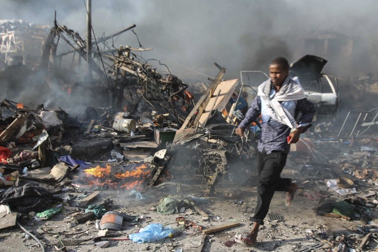 Image: A man runs through the scene of a massive explosion in front of Safari Hotel