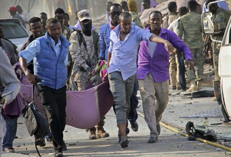 Image: Somalis use a sheet to carry a man wounded in a blast away to an ambulance