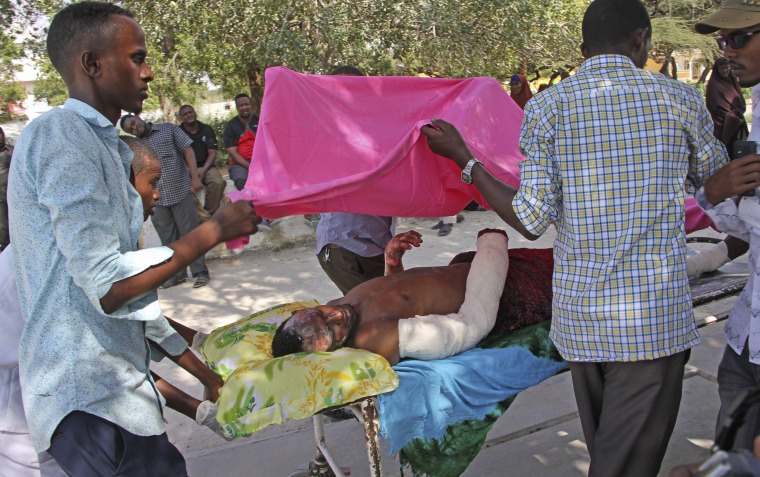 Image: Somalis help a wounded civilian at Medina hospital in Mogadishu
