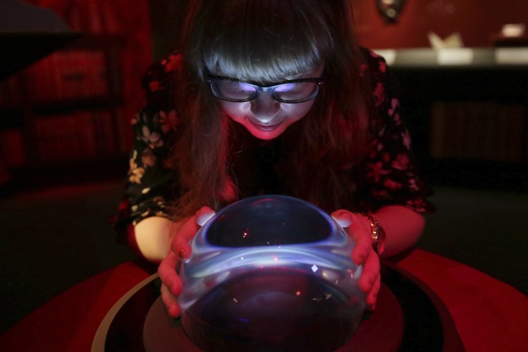 A member of British Library staff poses with a crystal ball for a picture at the "Harry Potter - A History of Magic" exhibition at the British Library, in London, Wednesday Oct. 18, 2017.