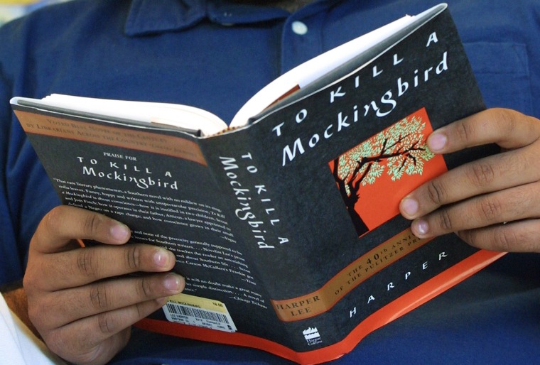 Image: A man holds a copy of Harper Lee's \"To Kill A Mockingbird\"