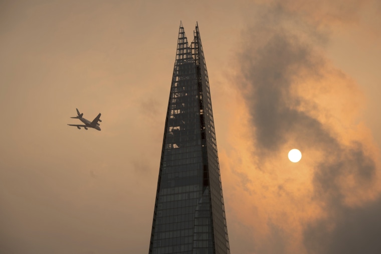Image: A plane flies past the Shard in central London, as the sky takes on an unusual orange colour