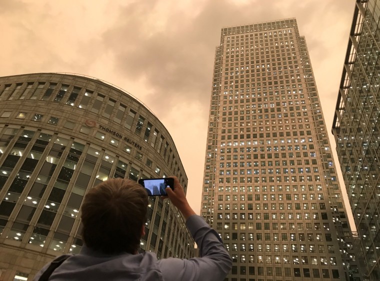 Image: The sky turns dark during mid-afternoon in the financial district of Canary Wharf