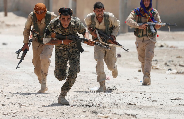 Image: Kurdish fighters from the People's Protection Units (YPG) run across a street in Raqqa