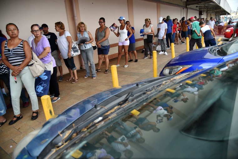 Image: People wait in a line to buy food at a supermarket in Humacao