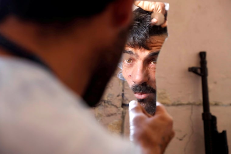 Image: A fighter of Syrian Democratic Forces fixes his hair using a broken mirror at the frontline in Raqqa