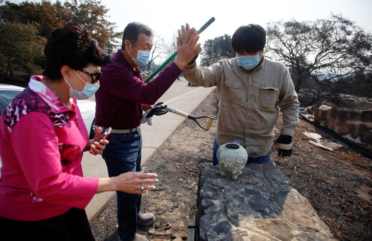Image: Lilly Ham, her husband Ted Ham and their son Alex Ham react after finding pottery in the rubble of Lilly and Ted's home that was destroyed in wildfire that tore through Santa Rosa, California