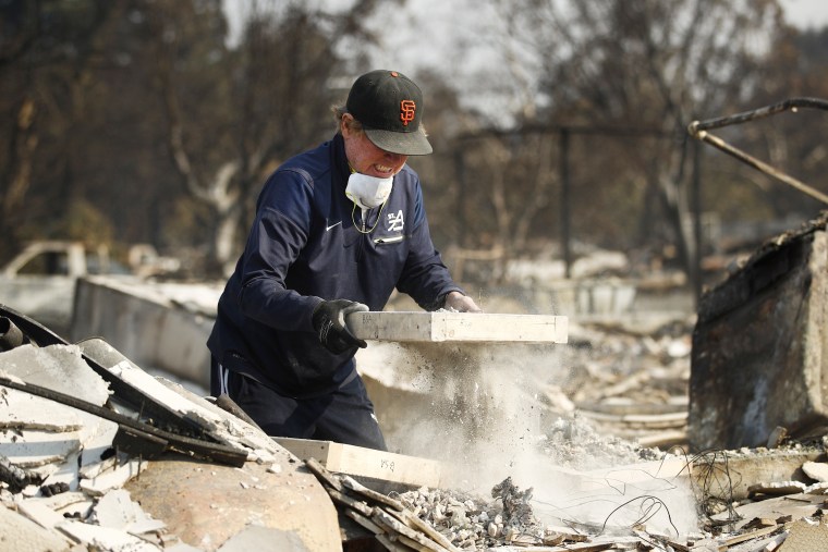 Image: Ed Curzon sifts debris to salvage anything he can from the rubble of his home