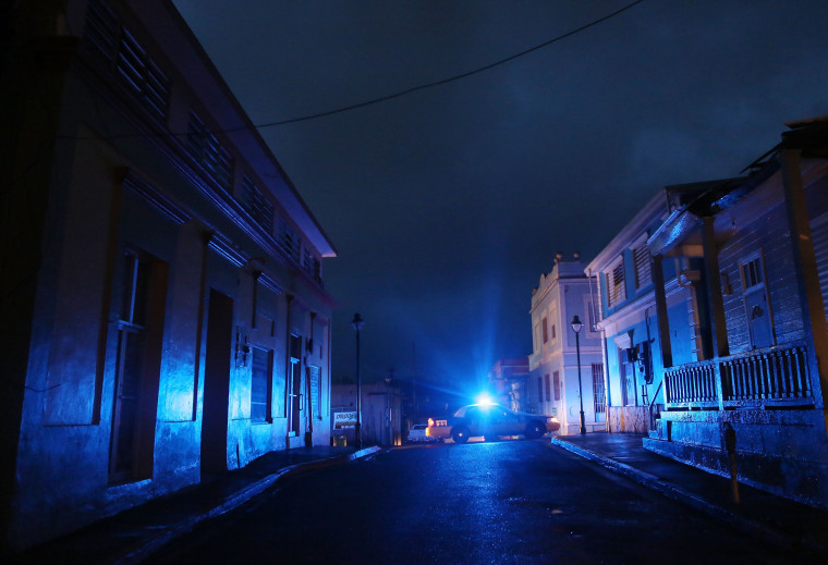 Image: A police car patrols on a darkened street