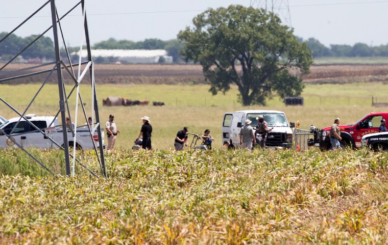 Image: The partial frame of a hot air balloon is visible above a crop field as investigators comb the wreckage of a Saturday morning accident that left 16 people feared dead when the balloon crashed in Maxwell