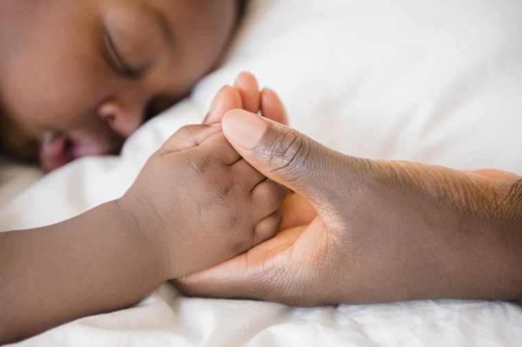 Image: Mother holding hand of sleeping baby