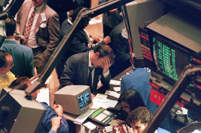 Image: A trader holds his head on the floor of the New York Stock Exchange as panic selling swept Wall Street
