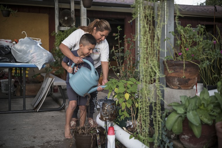 Image: Lidia Pena and her son water plants