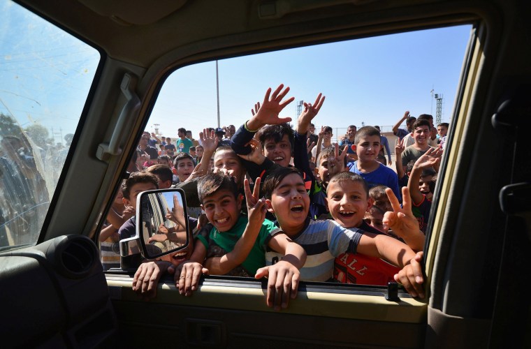Image: Iraqi boys gather on the road as they welcome Iraqi security forces members, who continue to advance in military vehicles in Kirkuk