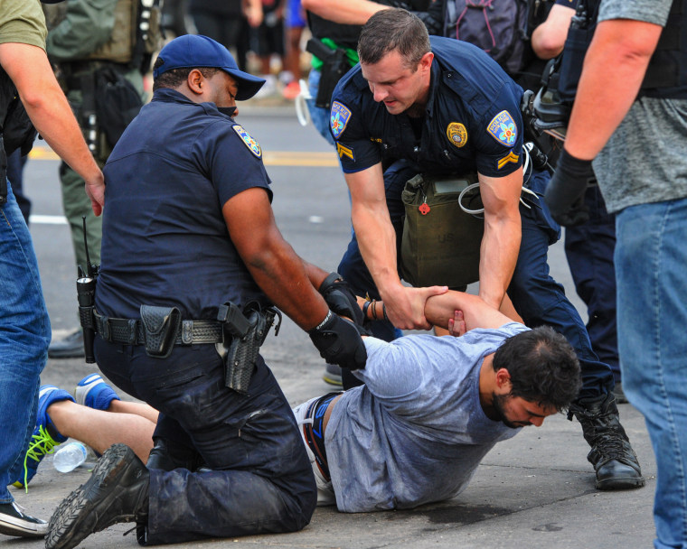 Police officers detain a protester as they try to clear streets while protesters were gathering against another group of protesters in Baton Rouge, La., Sunday, July 10, 2016. 