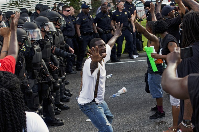 A man attempts to stop protesters from engaging with police in riot gear in front of the Police Department headquarters in Baton Rouge, La., after police attempted to clear the street on July 9, 2016. 