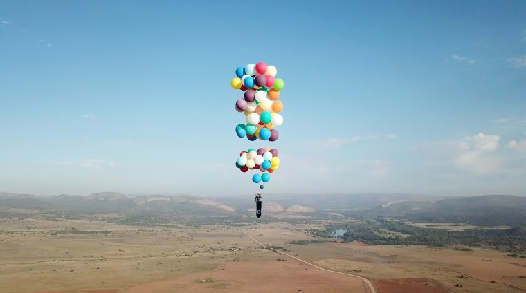 Image: Tom Morgan, from Bristol-based company The Adventurists, flies in a chair with large party balloons tied to it near Johannesburg, South Africa