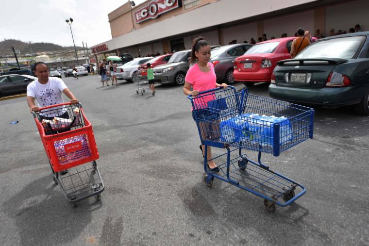 Image: Jose Rodriguez walks while carrying food he bought in a supermarket in Humacao