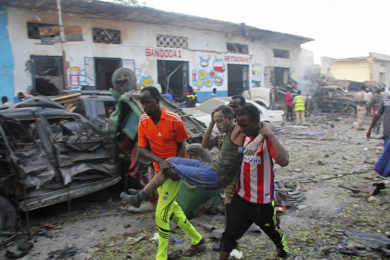 Image: Somalis carry away a man injured after a car bomb was detonated