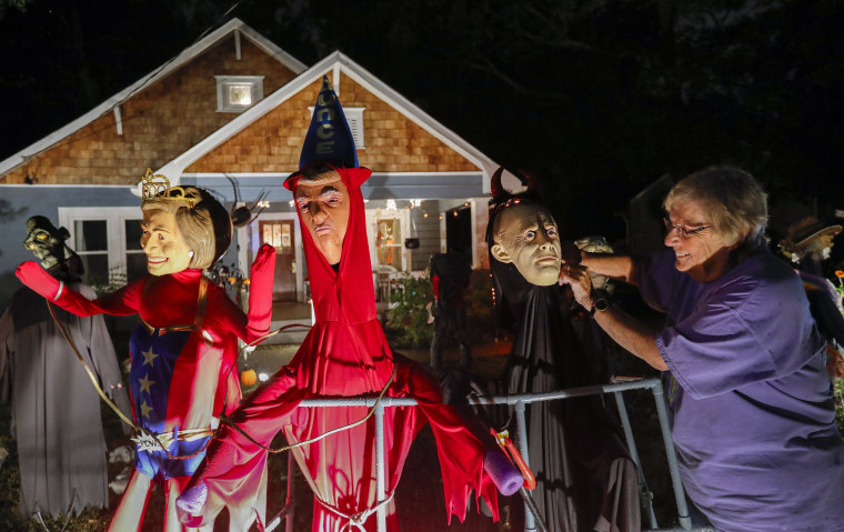 Image: Homeowner Gail Douglas adjusts a likeness of Russian leader Vladimir Putin erected beside one of President Donald Trump and another of Hillary Clinton at her home in Avondale Estates, Georgia on Oct. 28.