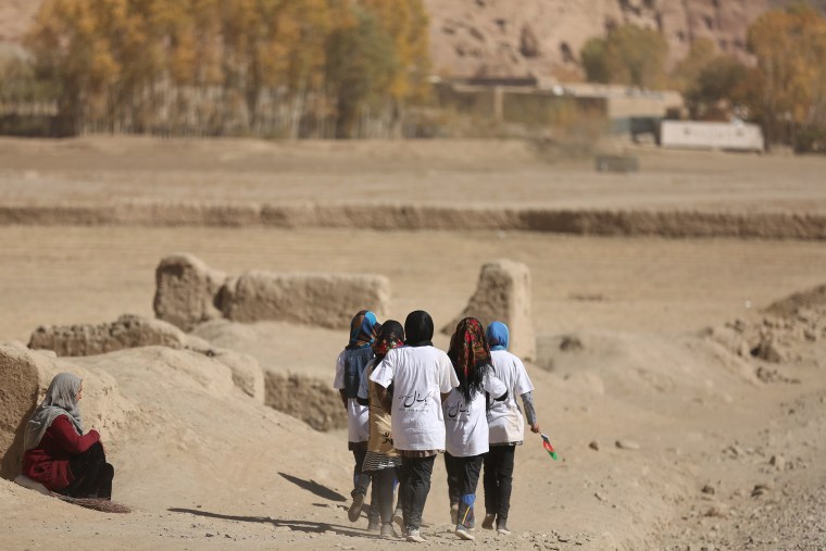 Image: Girls walk along a dirt road after running the Bamiyan Marathon