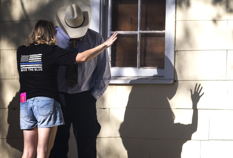 Image: A woman prays with a man after a fatal shooting